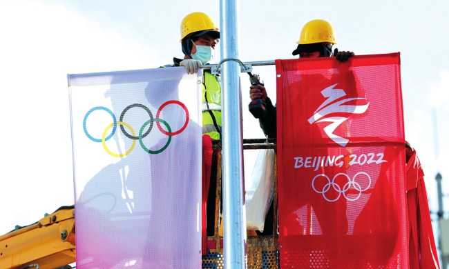 Punëtorët varin banderola me logon e Lojërave Olimpike në rrugët e Pekinit (Foto:VCG)