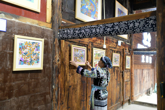 Le 19 mars, une villageoise arrange des peintures traditionnelles de l'ethnie Miao dans un magasin de souvenirs au xian de Longli, dans la préfecture autonome Buyi et Miao de Qiannan, dans la province du Guizhou (sud-ouest). 