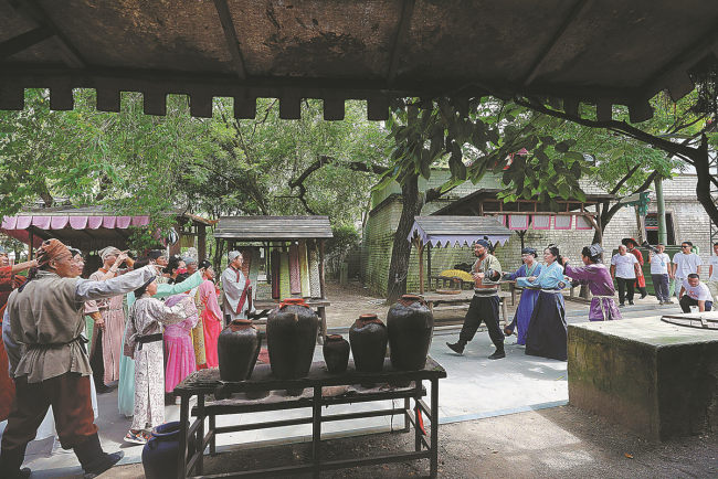 Τουρίστες, φορώντας παραδοσιακά κοστούμια Χαν, βιώνουν στιγμές δράσης σε μια γραφική περιοχή στα Hengdian World Studios στις 18 Ιουλίου. ZHU XINGXIN/CHINA DAILY