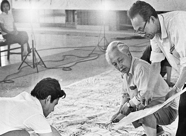 Ο Τζανγκ Ντινγκ (στην μέση), καλλιτέχνης και τότε πρόεδρος του Κεντρικού Ινστιτούτου Τεχνών και Χειροτεχνίας, ο Τζανγκ Γιμίν (αριστερά) και ο Τσου Τσι’εν (δεξιά) εργάζονται στην τοιχογραφία "Ο Νετζά ανακατεύει την θάλασσα" στο διεθνές αεροδρόμιο του Πεκίνου το καλοκαίρι 1979. [Φωτογραφία αρχείου ευγενική προσφορά του AADTHU]