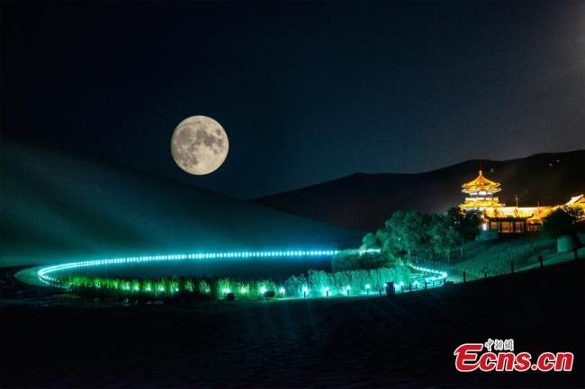 Ένα κρεμαστό «σούπερ φεγγάρι» πάνω από την τεράστια έρημο στο Ντουνχουάνγκ, στην επαρχία Γκανσού της βορειοδυτικής Κίνας, 21 Σεπτεμβρίου 2021. (Φωτογραφία: China News Service/Wang Binyin)