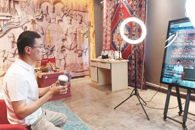 Ο Ερσάτ Ιμπραχίμ δείχνει το τσάι με τριαντάφυλλο του Χοτάν στους πελάτες του στο Διαδίκτυο. (People's Daily Online)