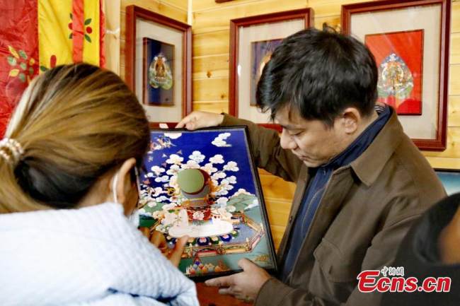 Ο κληρονόμος της πολιτιστικής κληρονομιάς της περιοχής Χουαλόνγκ με χαρακτηριστικό είδος τέχνης τα θάνγκκα, Γκενγκντένγκ Τσαϊράνγκ, δείχνει ένα έργο του στο εργαστήριό του στην κομητεία Χουαλόνγκ, στην επαρχία Τσινγκχάι της βορειοδυτικής Κίνας, 22 Νοεμβρίου 2021. (Φωτογραφία: China News Service)