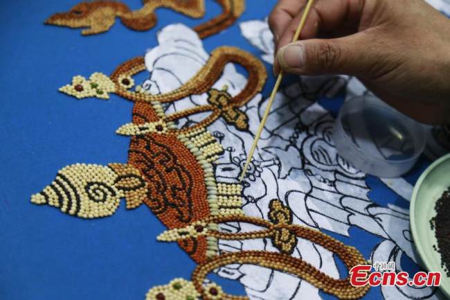 Μια Θιβετιανή φτιάχνει έργα τέχνης με κόκκους στην κομητεία Τζιαντζά, στον αυτόνομο θιβετιανό νομό Χουανγκνάν, στην επαρχία Τσινγκχάι της βορειοδυτικής Κίνας, 8 Δεκεμβρίου 2021. (Φωτογραφία: China News Service)