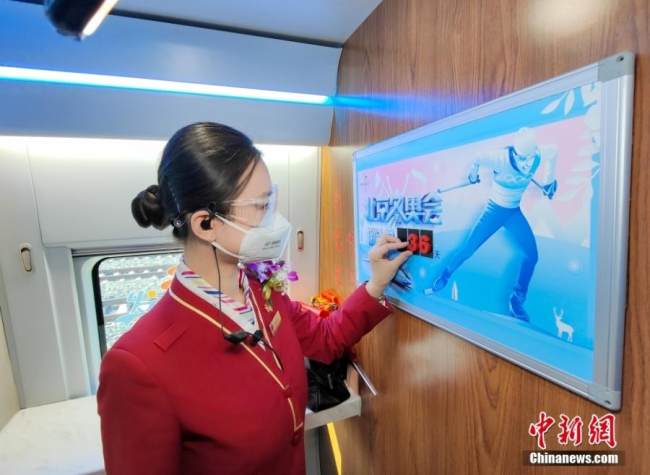 Μια αεροσυνοδός στο τρένο υψηλής ταχύτητας G8812 αλλάζει τον αριθμό αντίστροφης μέτρησης για την έναρξη των χειμερινών Ολυμπιακών Αγώνων του Πεκίνου, 30 Δεκεμβρίου 2021. (φωτογραφία/China News Service) 