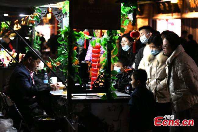 Κόσμος προσελκύεται από έργα ζωγραφικής με ζάχαρη, μια μορφή παραδοσιακής κινεζικής λαϊκής τέχνης, σε ένα κατάστημα ενός αρχαίου δρόμου στο Φουτζόου, πρωτεύουσα της επαρχίας Φουτζιέν στις 8 Ιανουαρίου 2022. (Φωτογραφία: China News Service)