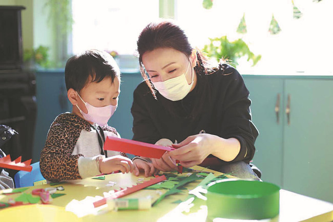 Μια εθελόντρια δείχνει σε ένα άρρωστο παιδί την τέχνη της χαρτοκοπτικής σε ένα σχολείο μέσα σε ένα νοσοκομείο της πρωτεύουσας. [Η φωτογραφία παρέχεται στην China Daily]