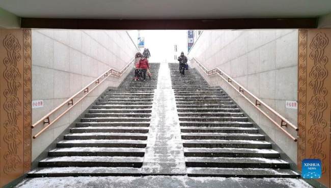 Περπατώντας ενώ χιονίζει σε μια στάση του Μετρό του Πεκίνου, στις 20 Ιανουαρίου 2022