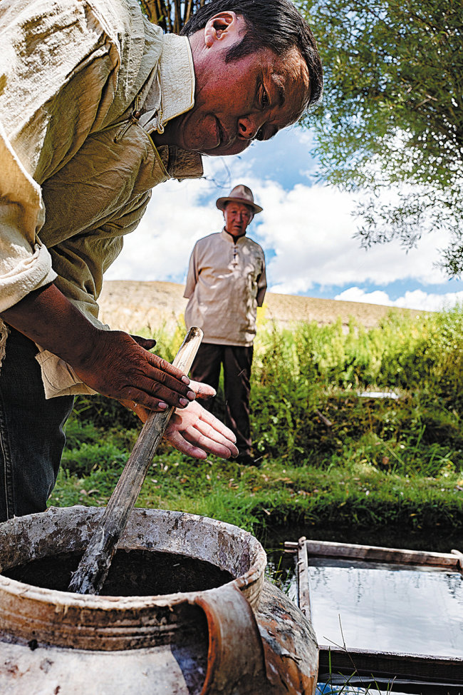 Ο Τσέτοπ (δεξιά) κοιτάζει τον γιο του Κελσάνγκ Τενζίν που φτιάχνει θιβετιανό χαρτί.[Φωτογραφία/Xinhua]