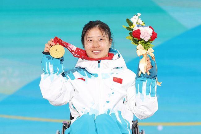 Η Γιανγκ Χονγκτσιόνγκ από την ομάδα της Κίνας ποζάρει με το χρυσό μετάλλιό της για σκι μεσαίας απόστασης γυναικών στην πλατεία ολυμπιακής βράβευσης στο Τζανγκτζιακόου στην επαρχία Χεμπέι της βόρειας Κίνας, 12 Μαρτίου 2022. /CFP