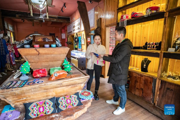 Επισκέπτης (αριστερά) επιλέγει προϊόντα Σιλανκαπού, ένα παραδοσιακό είδος υφάσματος μπροκάρ της εθνότητας των Τουτζιά, στην πόλη Σιαονανχάι του Τσιεντζιάνγκ στην πόλη Τσονγκτσίνγκ της νοτιοδυτικής Κίνας, στις 22 Μαρτίου 2022.