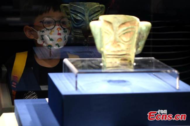 Ένα αγόρι παρατηρεί μια χάλκινη μάσκα που έχει ανασκαφεί από τα ερείπια του Σανσινγκντούι στο Μουσείο Φουτζιέν, της πόλης Φουτζόου, στην επαρχία Φουτζιέν στην νοτιοανατολική Κίνα, στις 12 Μαΐου 2022. (Φωτογραφία: China News Service) 