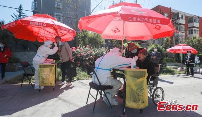 Iατρικό προσωπικό λαμβάνει δείγματα επιχρίσματος από κατοίκους του Πεκίνου για δοκιμή νουκλεϊκού οξέος στην συνοικία Σανλιτούν της περιοχής Τσαογιάνγκ στην πρωτεύουσα της Κίνας, στις 15 Μαΐου 2022. (Φωτογραφία: China News Service)