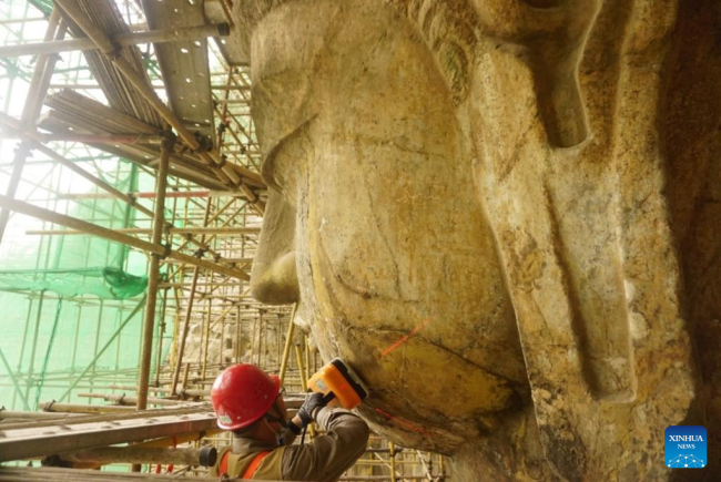 Αχρονολόγητη φωτογραφία αρχείου δείχνει έναν αρχαιολόγο να εξετάζει το πρόσωπο ενός αγάλματος του Βούδα στο Σπήλαιο Φενγκσιανσί των Σπηλαίων Λονγκμέν στην επαρχία Χενάν της κεντρικής Κίνας. (Xinhua)