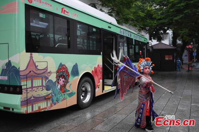Ένα παιδί δίνει παράσταση καντονέζικης όπερας μπροστά από ένα θεματικό λεωφορείο στο Γκουανγκτζόου (Καντόνα), στην επαρχία Γκουανγκντόνγκ της νότιας Κίνας, 8 Ιουνίου 2022. (Φωτογραφία: China News Service)