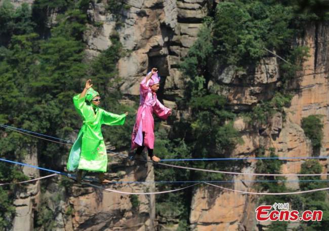 Σχοινοβάτες ντυμένοι με παραδοσιακές κινέζικες φορεσιές διαγωνίζονται στο Εθνικό Δασικό Πάρκο Τζανγκτζιατζιέ στην επαρχία Χουνάν της κεντρικής Κίνας, 10 Ιουλίου 2022. (Φωτογραφία: China News Service)