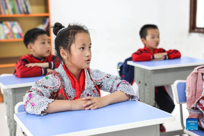 Η Γιανγκ Γιαμένγκ, παρακολουθεί μάθημα με τους συμμαθητές της σε ένα δημοτικό σχολείο στο χωριό Χουαγού της πόλης Σινρέν Μιάο, στην πόλη Τσιανσί της επαρχίας Γκουιτζόου της νοτιοδυτικής Κίνας, 1 Ιουνίου 2022.